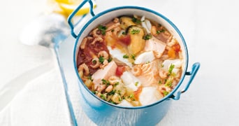 Visstoofpot met zalm, mosselen, garnalen en groenten in een blauwe pan.