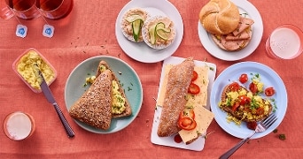 Ontbijt met diverse broodjes en spreads op een gedekte tafel.