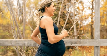 Zwangere vrouw in sportkleding geniet van een herfstdag buiten.