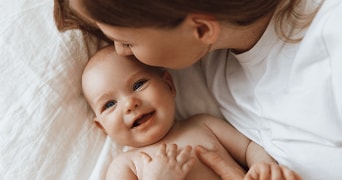 Moeder die een baby knuffelt op beddengoed.