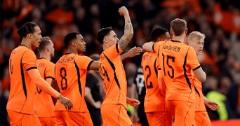 Voetballers van het Nederlands elftal in oranje tenue vieren samen een doelpunt tijdens een wedstrijd.