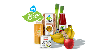 Biologische producten van Albert Heijn, waaronder penne, kokosmelk, passata di pomodoro, groentesap, bananen, een rode appel en prei