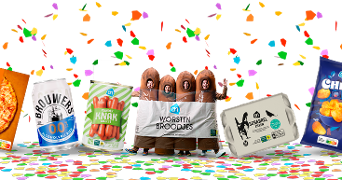 Personen verkleed als worstenbroodjes tussen populaire Albert Heijn producten zoals pizza, Brouwers alcoholvrij bier, knakworst, scharreleieren en chips, met kleurrijke confetti op de achtergrond.