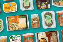 Verschillende Albert Heijn huismerk maaltijden, sauzen en verse ingrediënten tegen een zwarte achtergrond