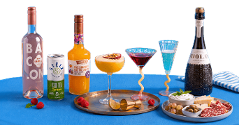 Dranken en cocktails met flessen wijn, een blikje ijsthee, een fles passievruchten martini, en een fles mousserende wijn, geserveerd met een borrelplank met kaas, vleeswaren, olijven en dips op een blauwe ondergrond.