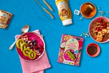 Verschillende ontbijtproducten van Albert Heijn, waaronder smoothie bowl mix, havermout, fruit en thee, gepresenteerd met ontbijtkommen en ingrediënten zoals kiwi, bessen en chiazaad.