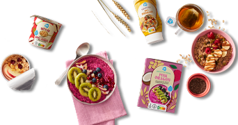 Verschillende ontbijtproducten van Albert Heijn, waaronder smoothie bowl mix, havermout, fruit en thee, gepresenteerd met ontbijtkommen en ingrediënten zoals kiwi, bessen en chiazaad.