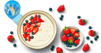 Kom yogurt met aardbeien en bosbessen, met glas water met schijfje citroen.