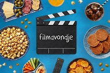 Afbeelding van verschillende snacks en drankjes, waaronder popcorn, stroopwafels, chips, groenten met dip, kaas en worst met crackers, pizza, frisdrank en sap, naast een afstandsbediening en een filmklapper met de tekst "filmavondje".
