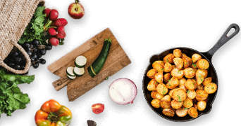 Een koekenpan met gekruide gebakken aardappeltjes, omringd door verse groenten zoals radijsjes, tomaten, courgette en zwarte bessen, naast een gesneden rode ui en een snijplank.