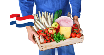 Persoon in blauwe overall houdt een houten krat met Nederlandse vlag vast, gevuld met asperges, aardbeien, tomaten, een appel, een komkommer, ham, kaas en verse peterselie.
