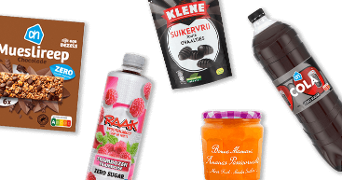 Vijf producten zonder toegevoegde suiker, waaronder AH mueslireep chocolade, Raak frambozen vruchtensiroop zero sugar, Klene suikervrije zoutjes, AH cola zero sugar en Bonne Maman ananas-passievrucht jam