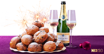 Een schaal met oliebollen naast een fles Diane de Frion champagne en twee glazen, met vuurwerk op de achtergrond.