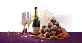 Feestelijke oud en nieuw setting met een schaal oliebollen, een fles Grande Pierre champagne, twee champagneglazen en vuurwerk op de achtergrond