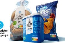 Altijd laag geprijsde AH producten: een verpakking volkoren schnittbroodjes, een bak Zaanse Hoeve Griekse stijl yoghurt 10% vet, en een zak AH Ribbel paprika chips, met het Prijsfavorieten logo en Nutri-Score labels.