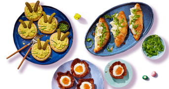 Verschillende paasbrunch gerechten, waaronder gevulde eieren in bladerdeeg, broodjes met roomkaas en rucola, en gepaneerde eieren met dooier, geserveerd op kleurrijke borden.