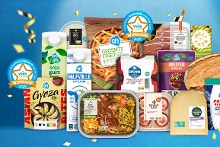 Winnaars van de Vries Vers verkiezing 2025 bij Albert Heijn: diverse bekroonde AH-huismerkproducten, zoals sojayoghurt, halfvolle melk, groentefriet, Gyoza, kant-en-klaarmaaltijden, kaas en meer, uitgestald met confetti en medailles tegen een blauwe achtergrond.