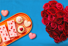 Bordje met Valentijn producten, macarons, tompouce en kleine gebakjes met hartjes. En een grote bos rozen in hartjesvorm