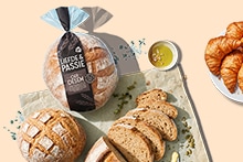 Heelbrood Liefde & Passie oerdesem, gesneden oerdesembrood, kleine bol oerdesembrood en een wit bord met croissants.