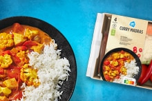 Een bord met curry madras met ernaast het verspakket van curry madras.