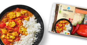Een bord met curry madras met ernaast het verspakket van curry madras.