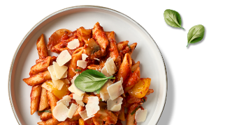 Penne pasta met tomatensaus, gegrilde groenten, Parmezaanse kaas en verse basilicum op een wit bord