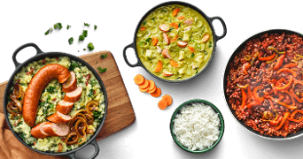 Drie verschillende gerechten in pannen: stamppot met rookworst, een kom romige groentensoep en een pan chili con carne met rijst.