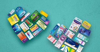 Verzameling van diverse gezondheidsproducten en medicijnen, waaronder merken als Zovirax, Strepsils, en Hansaplast, gerangschikt in de vorm van een hart op een blauwe achtergrond.