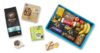 Diverse selectie van ontbijt- en tussendoorproducten, waaronder Perla koffie, een notenreep, biologische citroengemberthee, diverse soorten L'OR koffiecups, Biscoff koekjes, gember, en een blauwe krat gevuld met vers fruit zoals appels, bananen en kiwi’s.