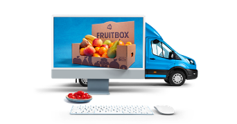 Computerbeeldscherm met een afbeelding van een Albert Heijn Fruitbox gevuld met diverse vruchten, naast een Albert Heijn bezorgbus en een toetsenbord met een schaaltje kersen op de voorgrond.