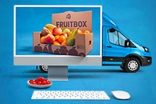 Albert Heijn Fruitbox gepresenteerd op een computerscherm met een bezorgbusje en een schaaltje tomaten op de voorgrond.