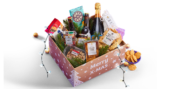 Kerstpakket met luxe etenswaren, snacks, champagne en andere feestelijke producten in een doos met de tekst 'Merry X-MAS', versierd met kerstballen en kerstlampjes.