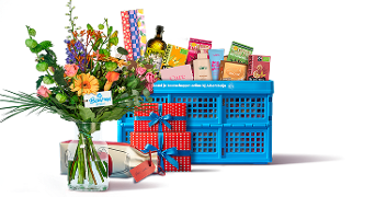 Boeket bloemen, cadeaus met blauwe strik en een blauwe boodschappenkrat gevuld met diverse producten, waaronder verzorgingsmiddelen, chocolade en drank, allemaal gepresenteerd als geschenk bij Albert Heijn.