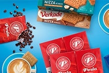 Blauwe Albert Heijn boodschappenkist gevuld met diverse producten, waaronder AH cola, Perla koffie, frisdrankflessen, thee, kauwgom en ontbijtgranen.