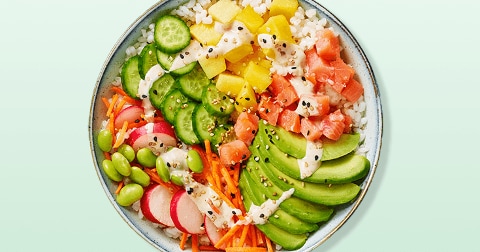 Poké bowl met zalm, avocado, komkommer, radijs, wortel, edamame, ananas en sesamzaadjes op een bedje van rijst, gegarneerd met een lichte dressing.