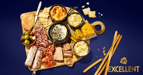 Borrelplank met verschillende soorten vleeswaren, kazen, olijven, dips en crackers, gepresenteerd als Albert Heijn Excellent assortiment.