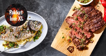 Pakket luxe XL met gegrilde vis en steak op een houten serveerplank.