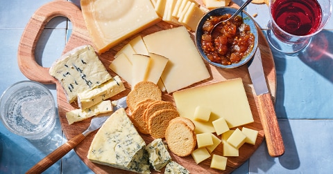 Kaasplank met diverse soorten kaas, toastjes, vijgenjam en een glas rode wijn.