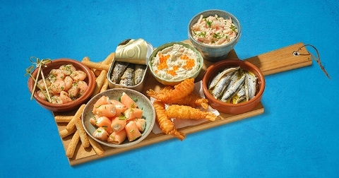 Houten plank met een assortiment zeevruchten, inclusief garnalen, zalmrolletjes, sardines, gefrituurde vis en dips.
