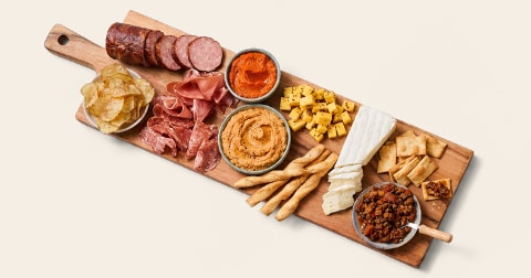 Borrelplank met diverse vleeswaren, kazen, dips, broodsticks, chips en toastjes.