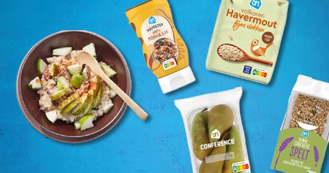 Havermout ontbijt met plakjes peer, pindakaas, AH volkoren havermout, AH conference peren, AH squeezer pindakaas en AH speltcrackers op een blauwe ondergrond