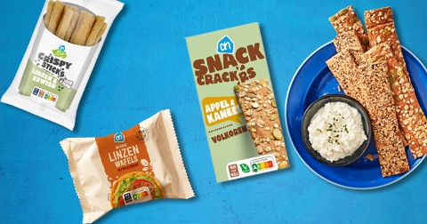 AH snack crackers appel & kaneel, AH crispy snack linzen en AH linzenwafels op een blauwe achtergrond, met een bord snack crackers en een schaaltje dip
