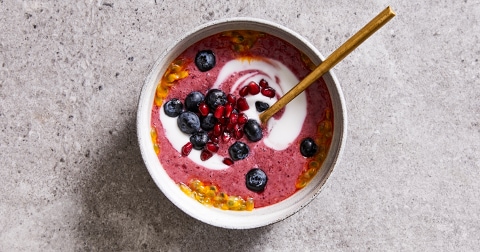 Kom met smoothiebowl, blauwe bes en granaatappelpitjes