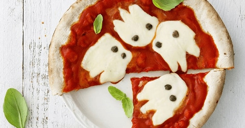 Pizza met tomatensaus en mozzarella in de vorm van spookjes, met basilicumblaadjes als garnering