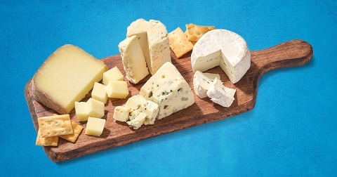 Kaasplank met verschillende soorten kaas en crackers op een houten snijplank.