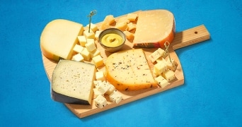 Kaasplank met diverse soorten kaas en mosterdsaus.