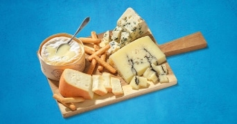 Kaasplank met blauwe kaas, camembert en diverse andere kazen geserveerd met knapperige stokjes.