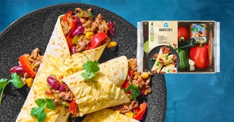 AH maaltijdpakket burrito's met gevulde wraps op een bord, omringd door groenten en verse kruiden