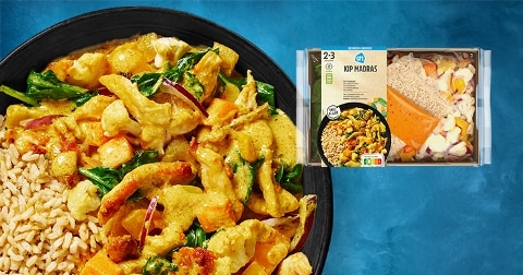 Maaltijdpakket Kip Madras van Albert Heijn met rijst, kip en groenten in een schaal, naast de verpakte inhoud met losse ingrediënten en etikettering.