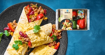 AH Burrito maaltijdpakket met gevulde wraps op een zwart bord, gevuld met paprika, rode bonen, mais en gehakt, gegarneerd met koriander